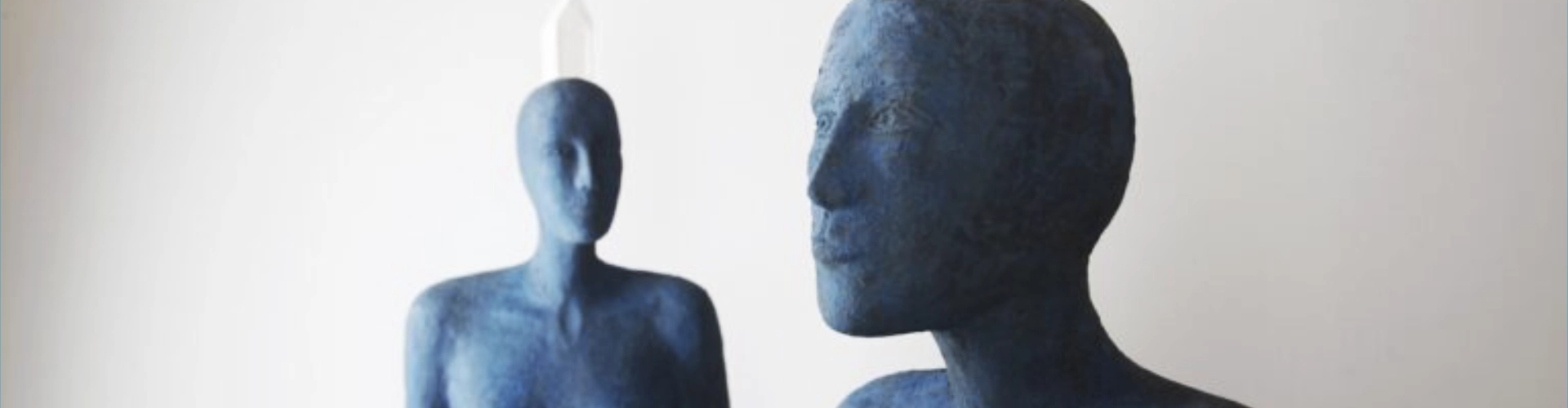 Sculpture de l'artiste Josette Taramarcaz, repésentant des corps bleutés avec une pierre blanche en équilibre sur leur tête