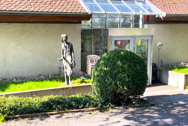 Vue sur l'entrée de l'Espace Culturel, avec son allée verdoyante , habitée par une sculpture représentant un mandiant
